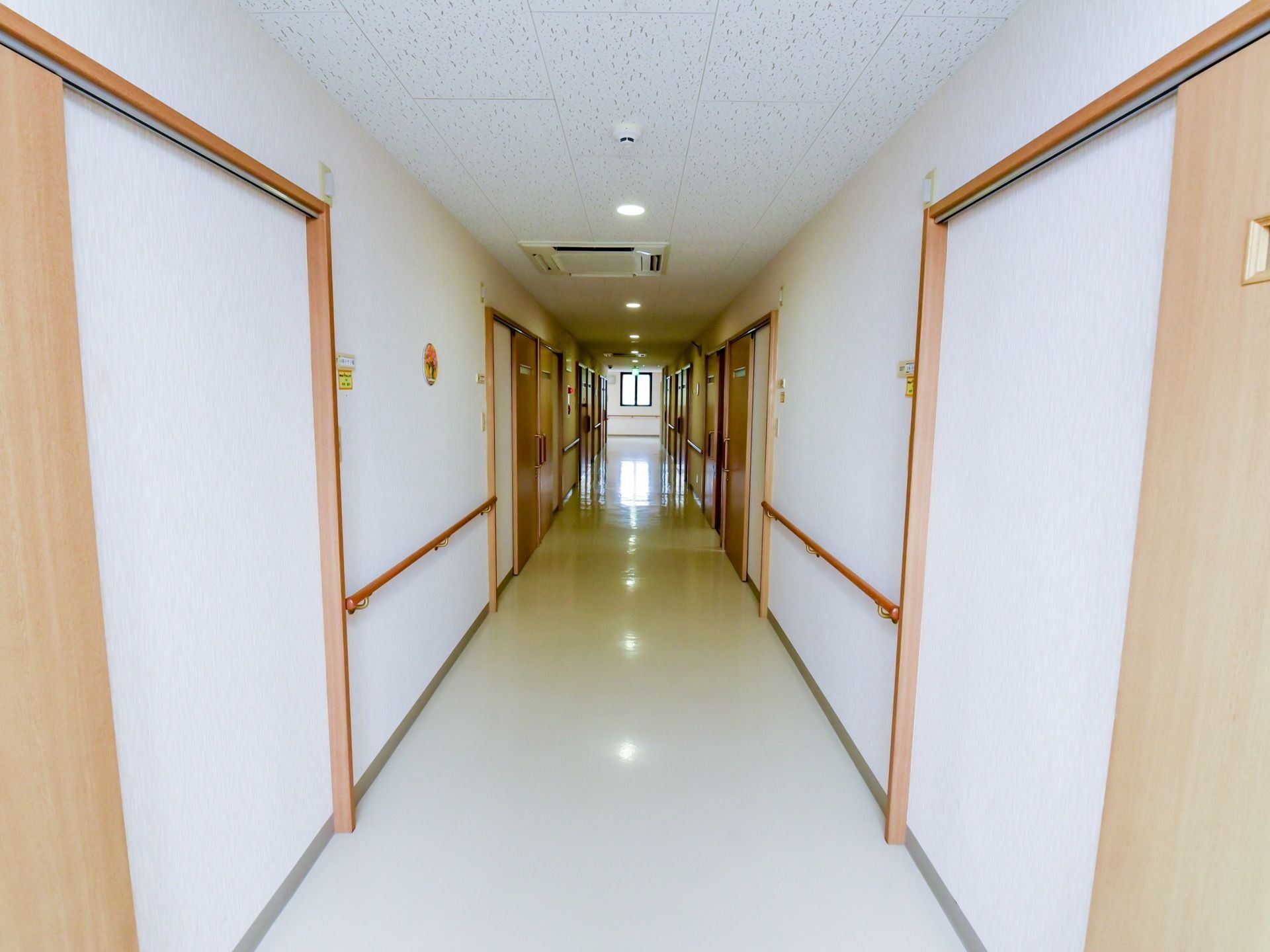 通路の両側の壁には、長い手すりが取り付けられている。オフホワイトの床は、段差のないバリアフリー構造になっている。