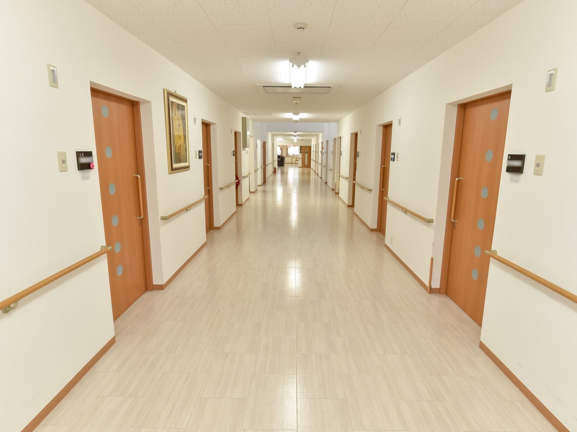 とても広い通路で、床や壁が白く明るい印象がある。両側の壁には手すりが設置されており、ドアは木目調の引き戸になっている。