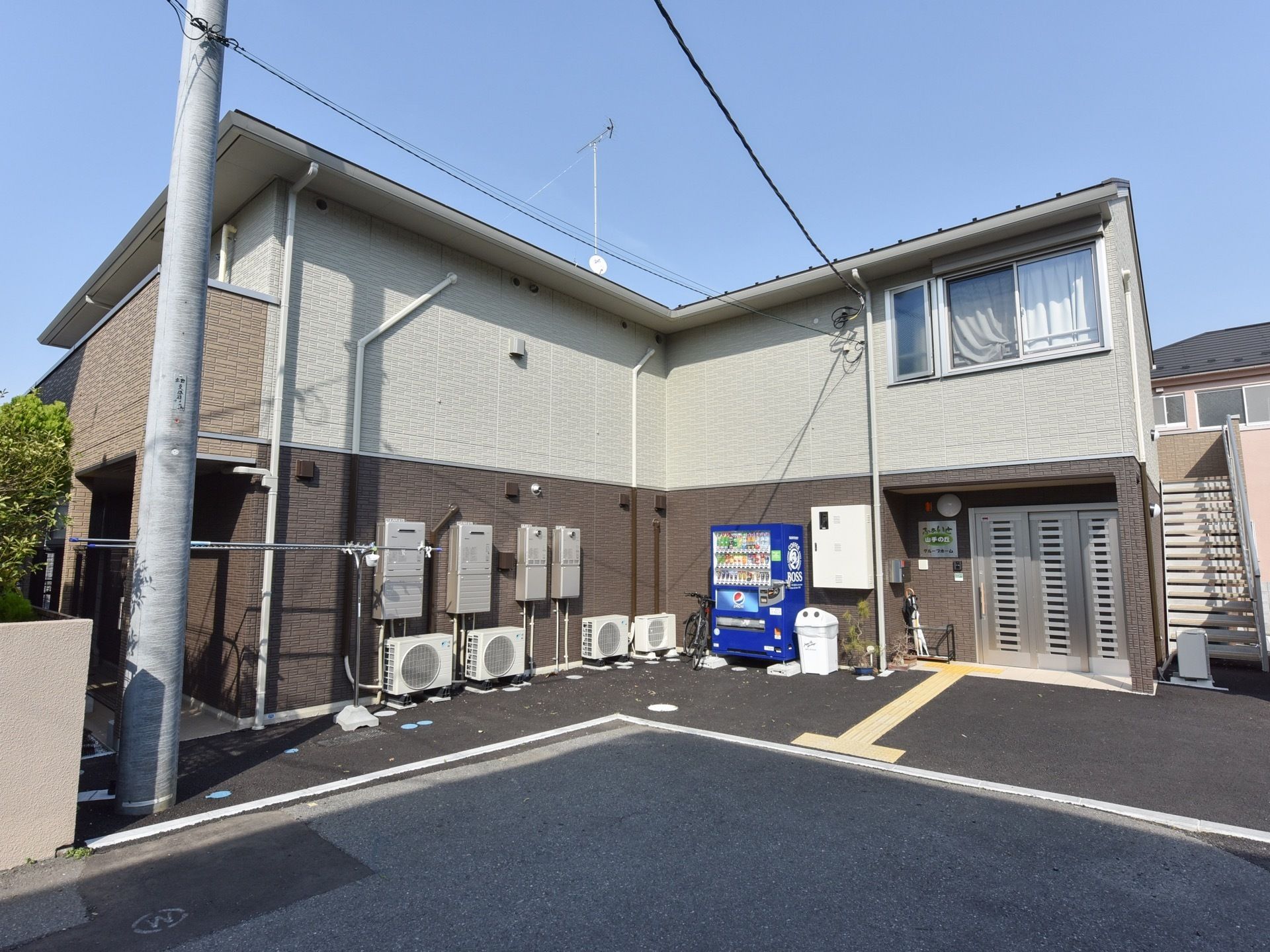 ブラウンが基調の外壁の２階建ての建物になっている。玄関前の通路には点字ブロックがあり、目が不自由な方も安心して移動することができる。