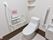 白い壁で清潔感のある明るいトイレである。温水洗浄便座になっており、操作ボタンが壁にあるので押しやすい。