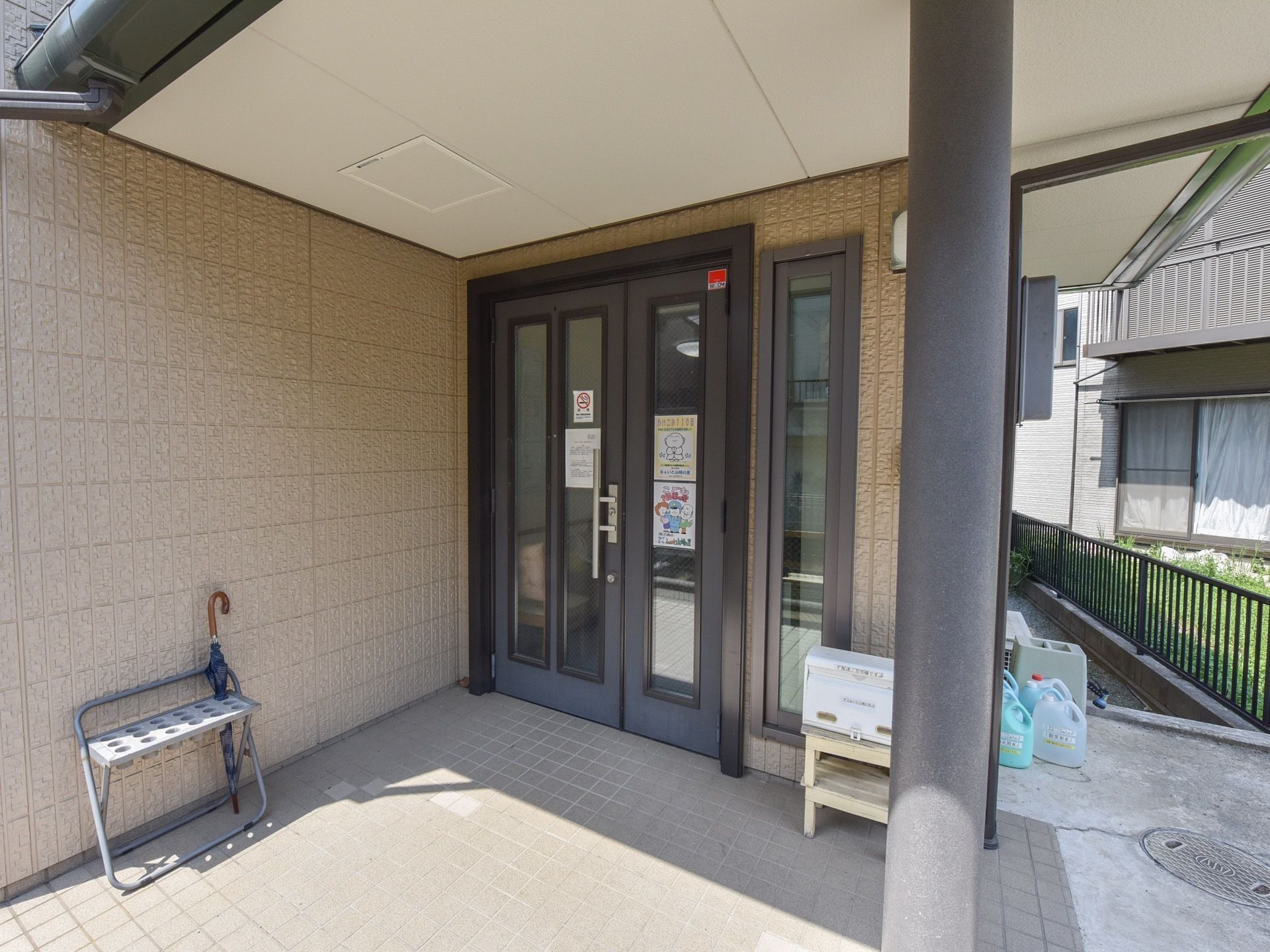 ドアの傍に、傘立てと郵便ポストが設置されたエントランス