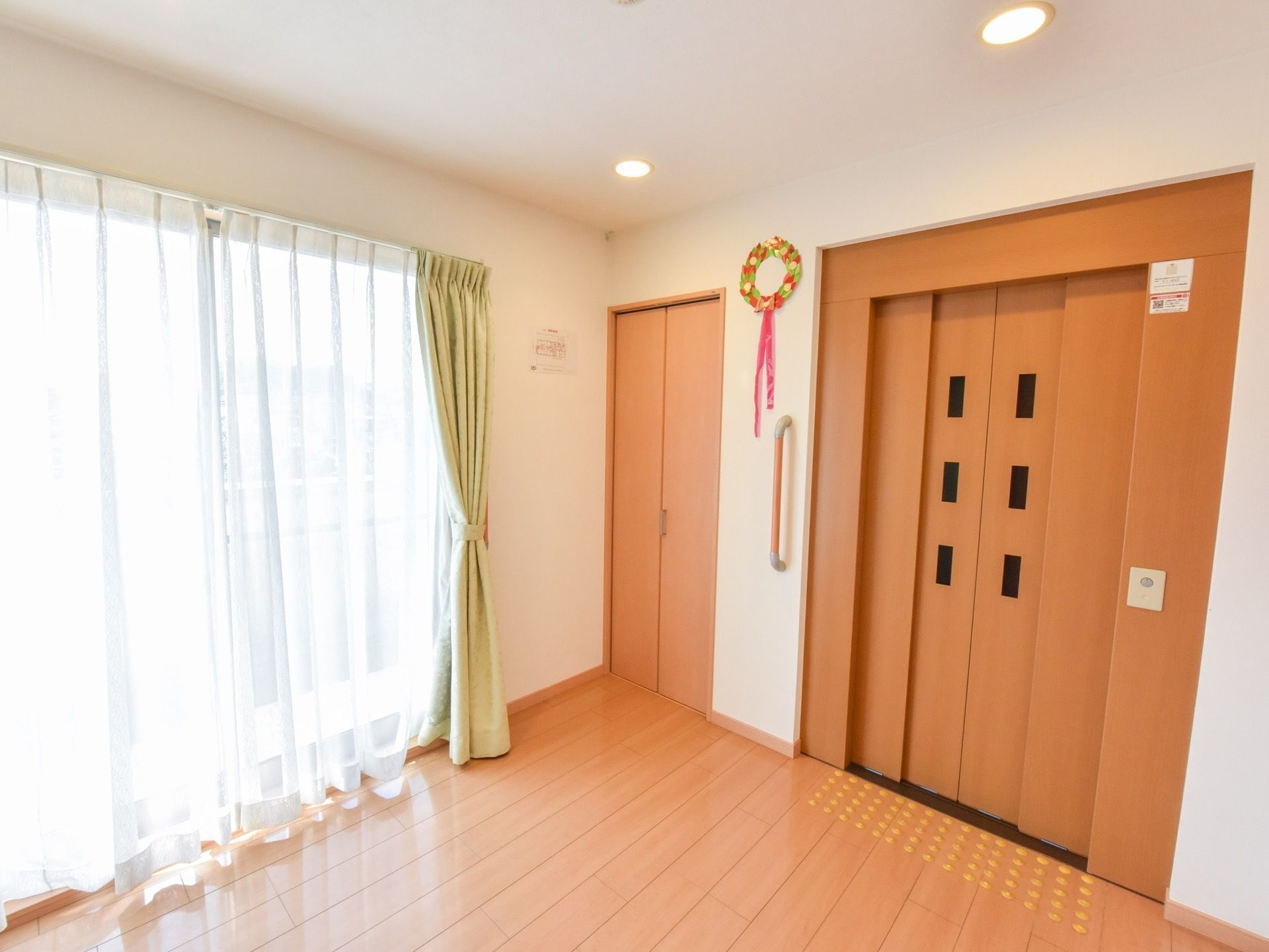 エレベーターの近くには大きな窓があり、ホールを明るくしている。エレベーターのドアは部屋のドアと同系色なので、馴染んでいる。