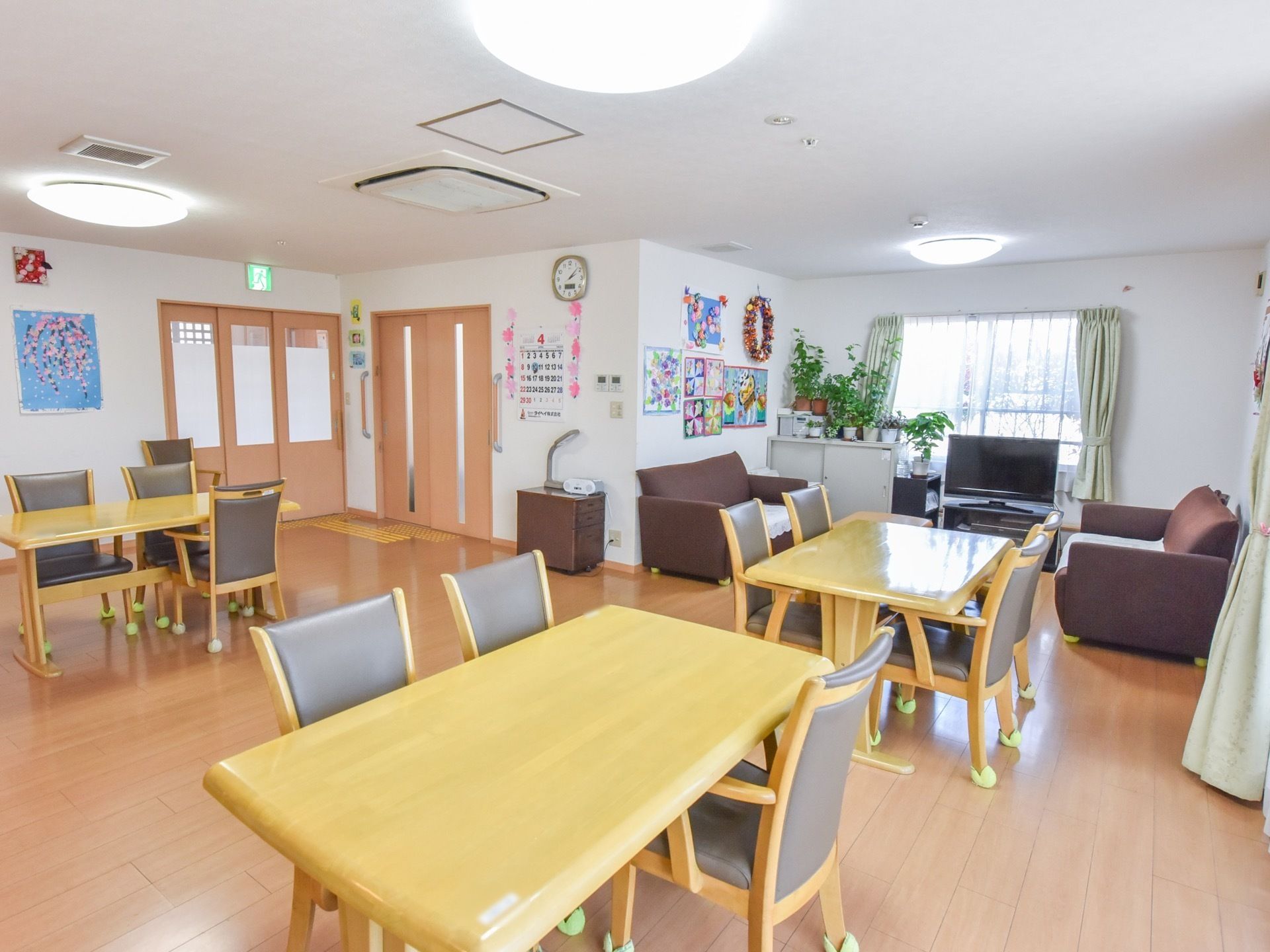 入居者様が集まる場所には、ソファーとテレビが用意されている。壁には、ペーパークラフトを多数展示して明るい雰囲気である。