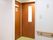 廊下の一角に共用トイレの入口がある。扉は木製の引き戸になっていて、壁には手すりが備えつけられている。