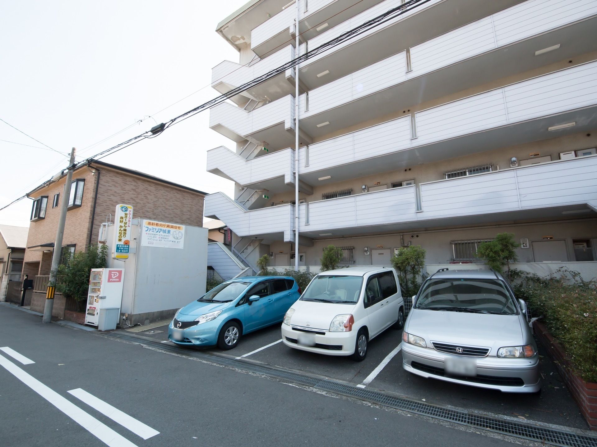 6階建ての白い外壁の建物は、閑静な住宅街にとけこむ落ち着いた佇まいである。幅の広い一方通行の道路に面しており、外出時も安全である。