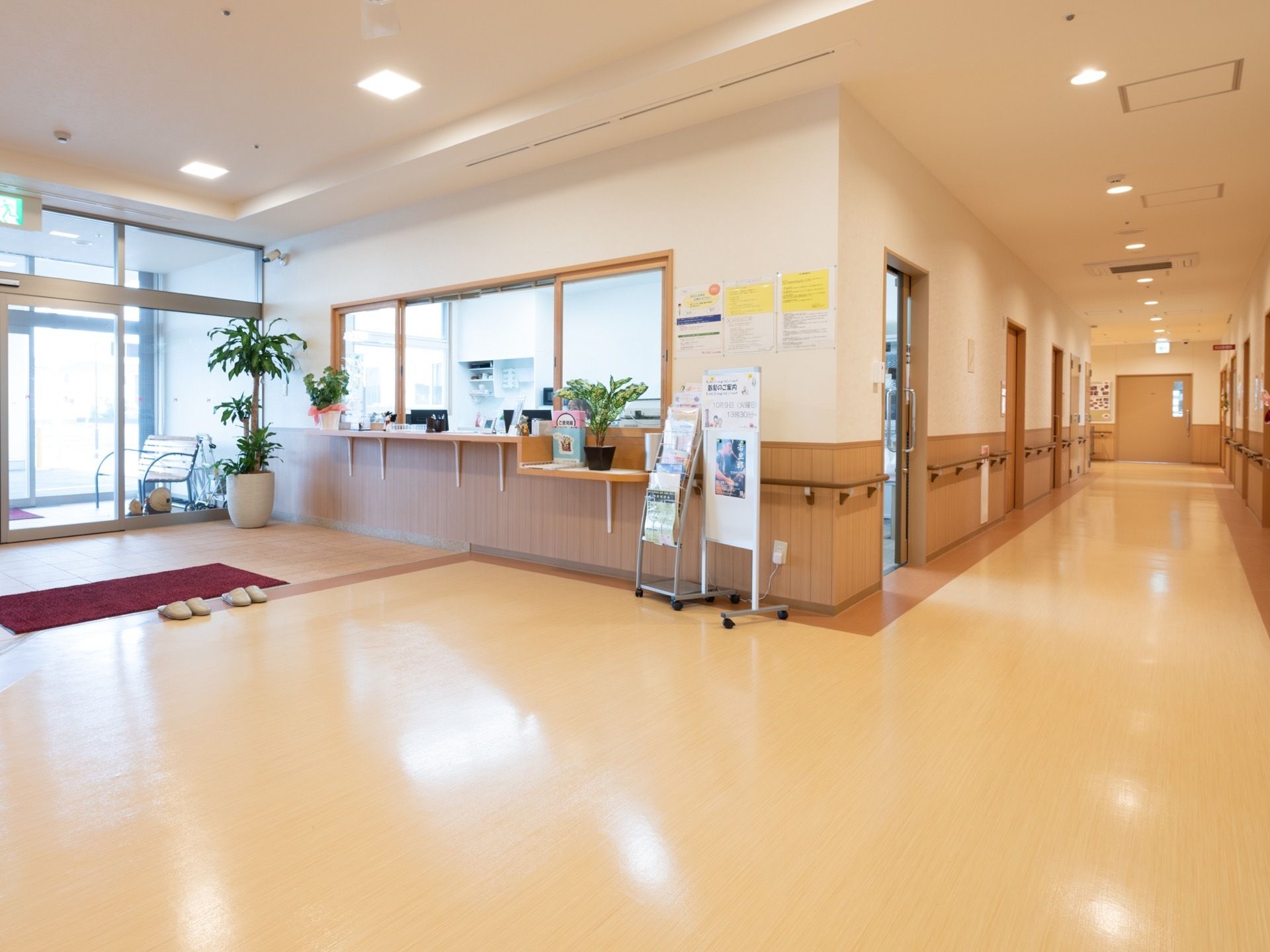 エントランスの横にスタッフの事務所があり受付の窓がある。その前に掲示板が立てられ、施設からのお知らせなどが貼り出されている。