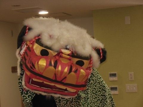 空調設備が整った部屋で、獅子舞が舞うイベントの風景