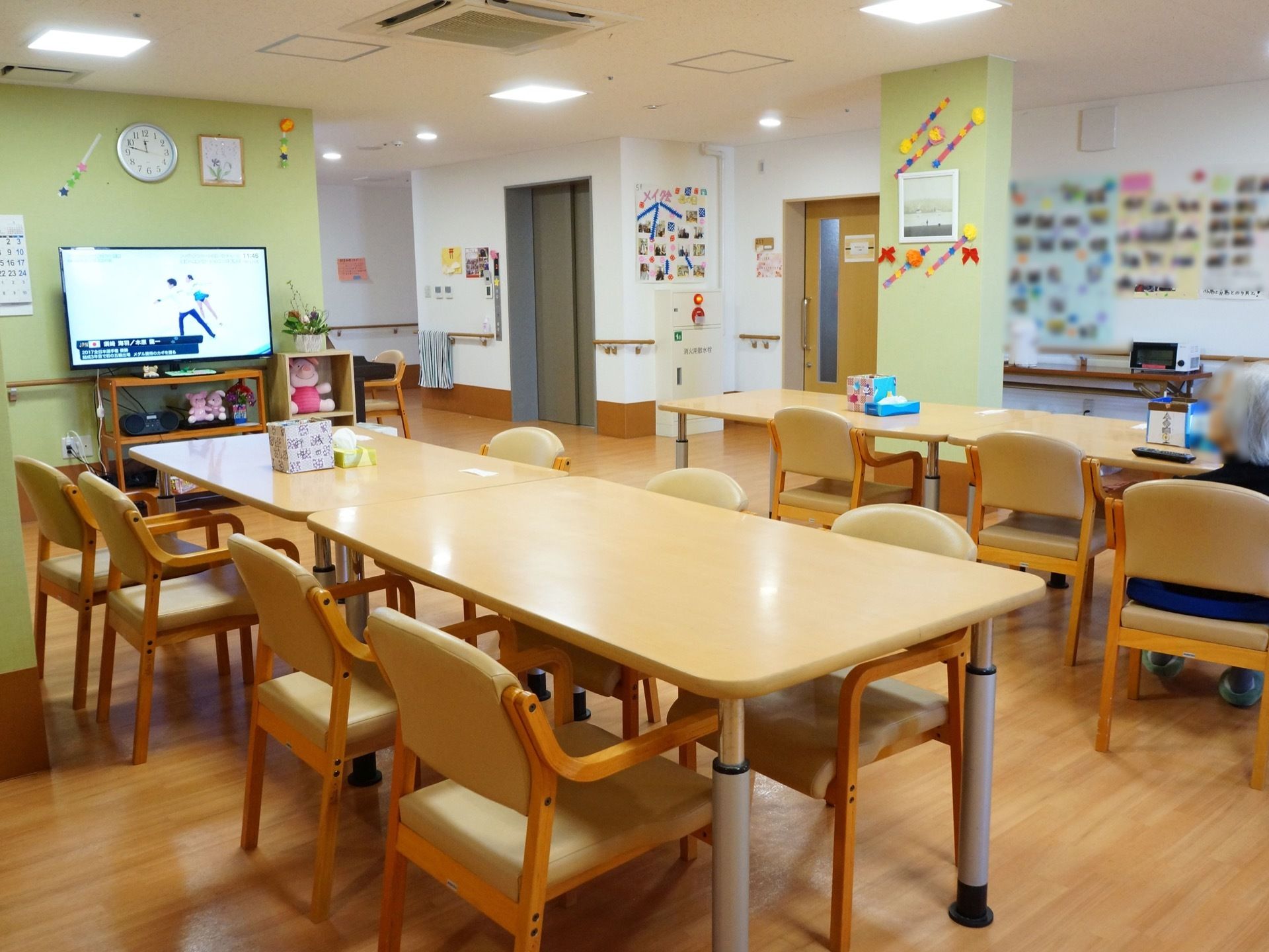 食堂の壁や柱は、ペールグリーンの優しい色合いである。壁際にはテレビがあり、その周りに可愛らしいぬいぐるみが置いてある。