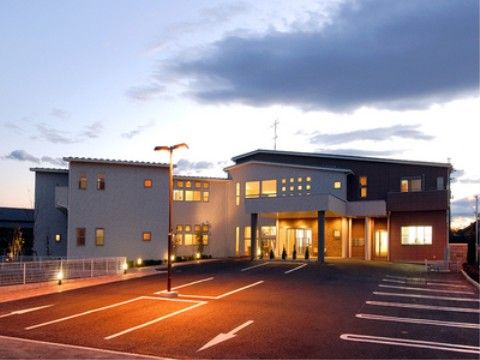 夜が近づき、照明が点灯されている施設の外観と駐車場