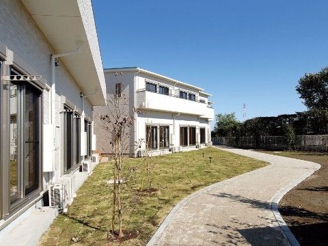 敷地内に芝生スペースや舗装された通路がある、施設の外観