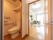 左側にはトイレがあり、奥には居室がある。居室内には照明が２か所設置され、窓からの採光も十分である。観葉植物とソファが設置されている。