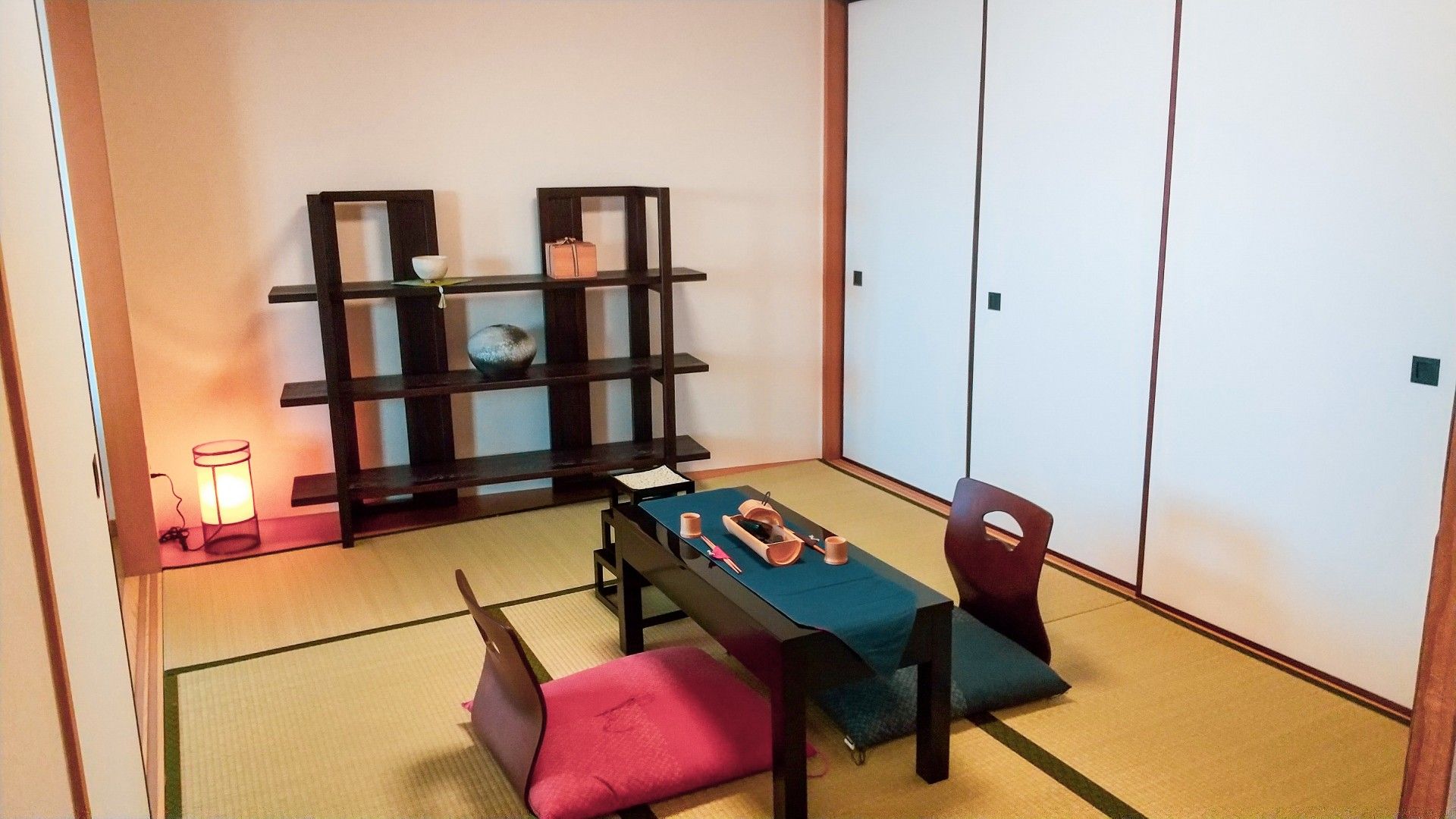 六畳ほどの和室である。中央にはテーブルがあり、座布団が二枚目向かい合う形で用意されている。テーブルの上にはテーブルクロスが敷かれている。
