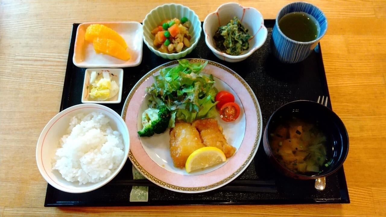 赤飯と焼き鮭、小鉢に盛られた野菜のおかずに箸とフォークが添えられている
