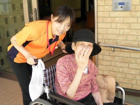 玄関にて、スタッフが押している車椅子に乗り移動している入居者様
