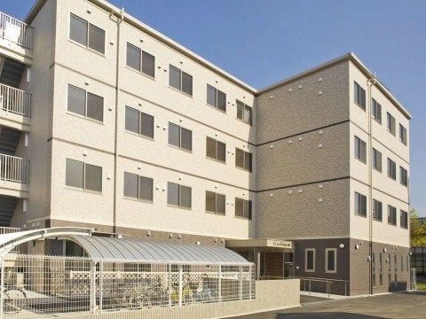 出っ張りの少ないシンプルな形状でレンガ調の壁を持つ、４階建ての建物