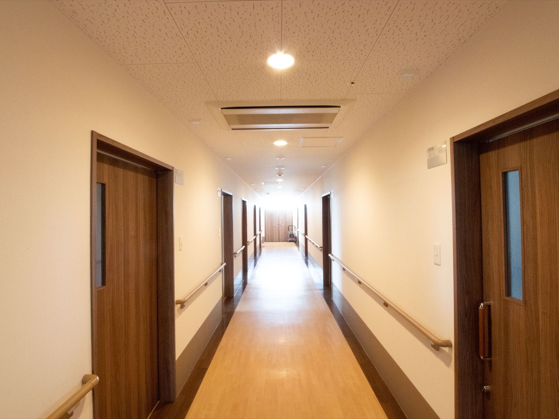 通路がまっすぐに続いている。通路の突き当りと、両側には部屋の扉が並んでいる。壁には長い手すりが取りつけられている。