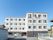 施設は４階建てで、各居室の窓が並んでいる。窓にはレースのカーテンがかけられている。外には洗濯物が干してある。