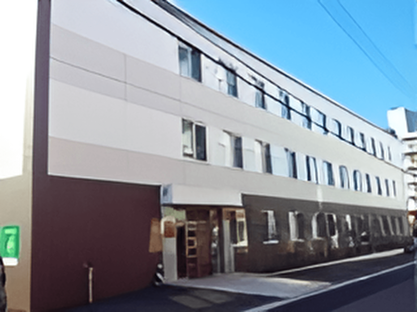 フラットなクリーム色の外壁の１階部分のみブラウンで塗装された建物