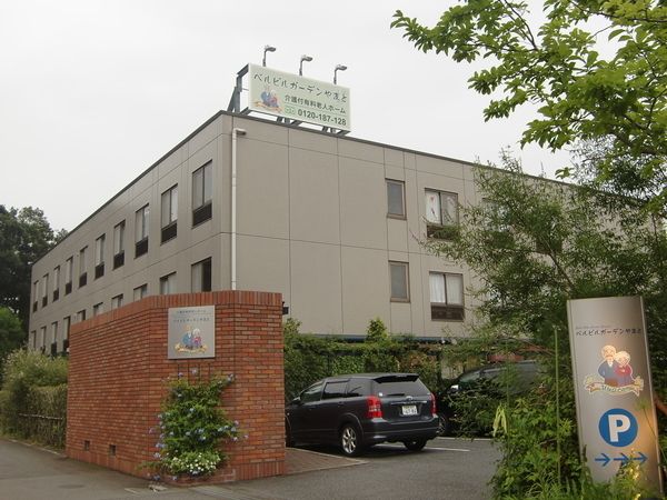 区画の仕切りに植込みやレンガ調の壁を用いた、グレーの外壁を持つ建物