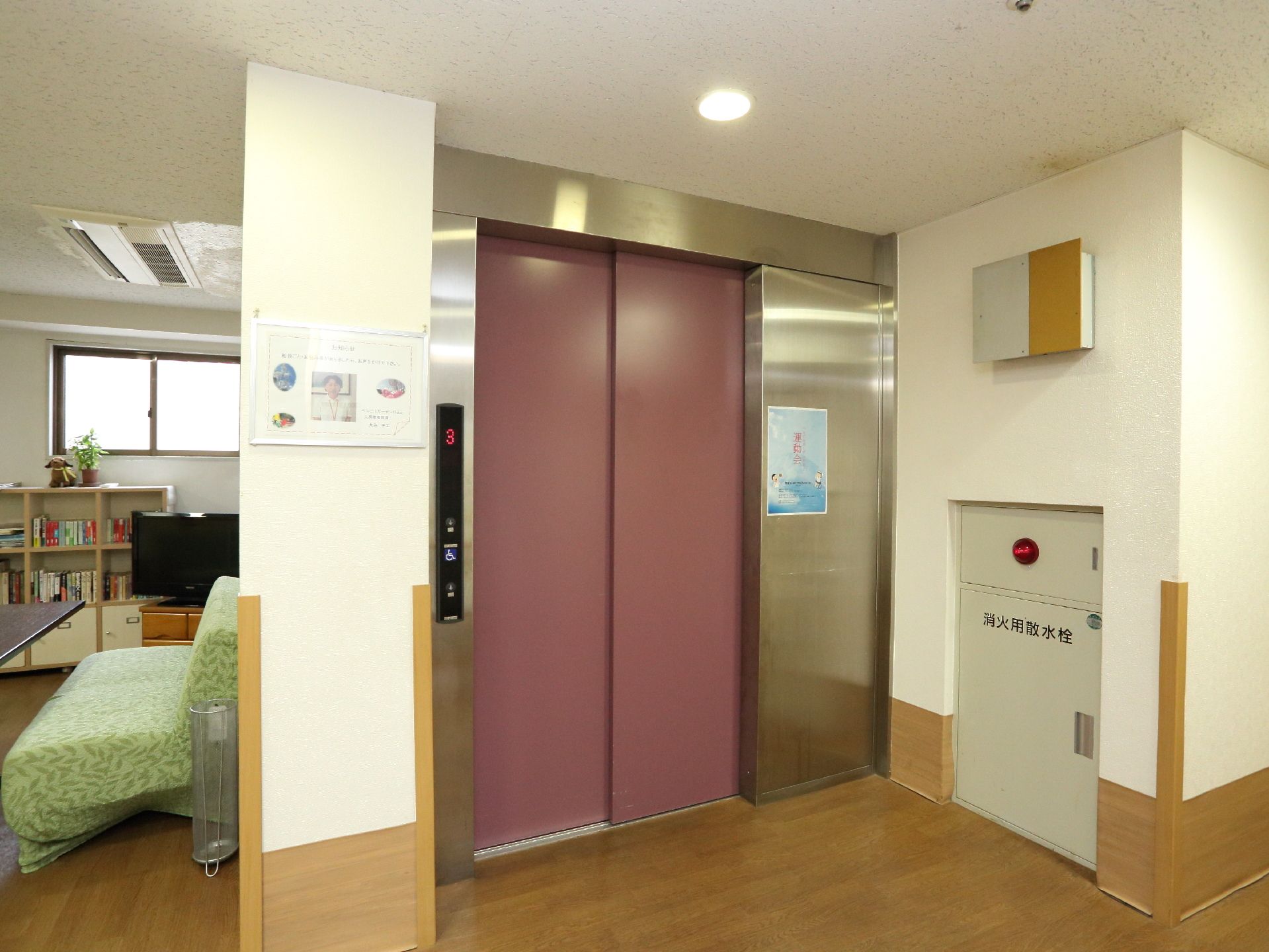 大きなエレベーターである。奥行きがあり、車椅子をご利用の方も乗り降りしやすい。横の壁に消火用水栓とスピーカーが設置されている。