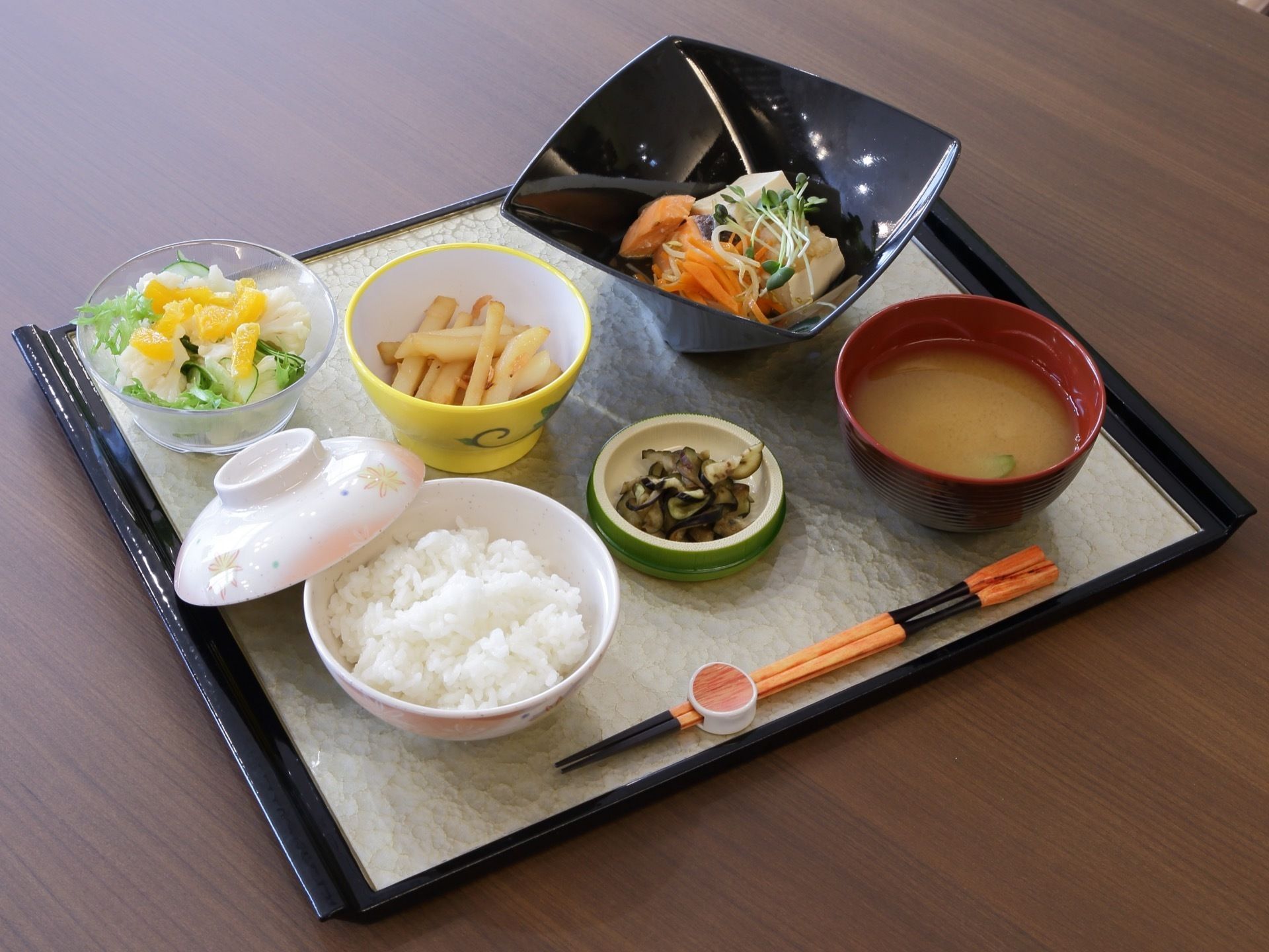 ある日の食事である。白ご飯、みそ汁、漬物、野菜サラダ、フライドポテト、煮魚といった和食メニューである。