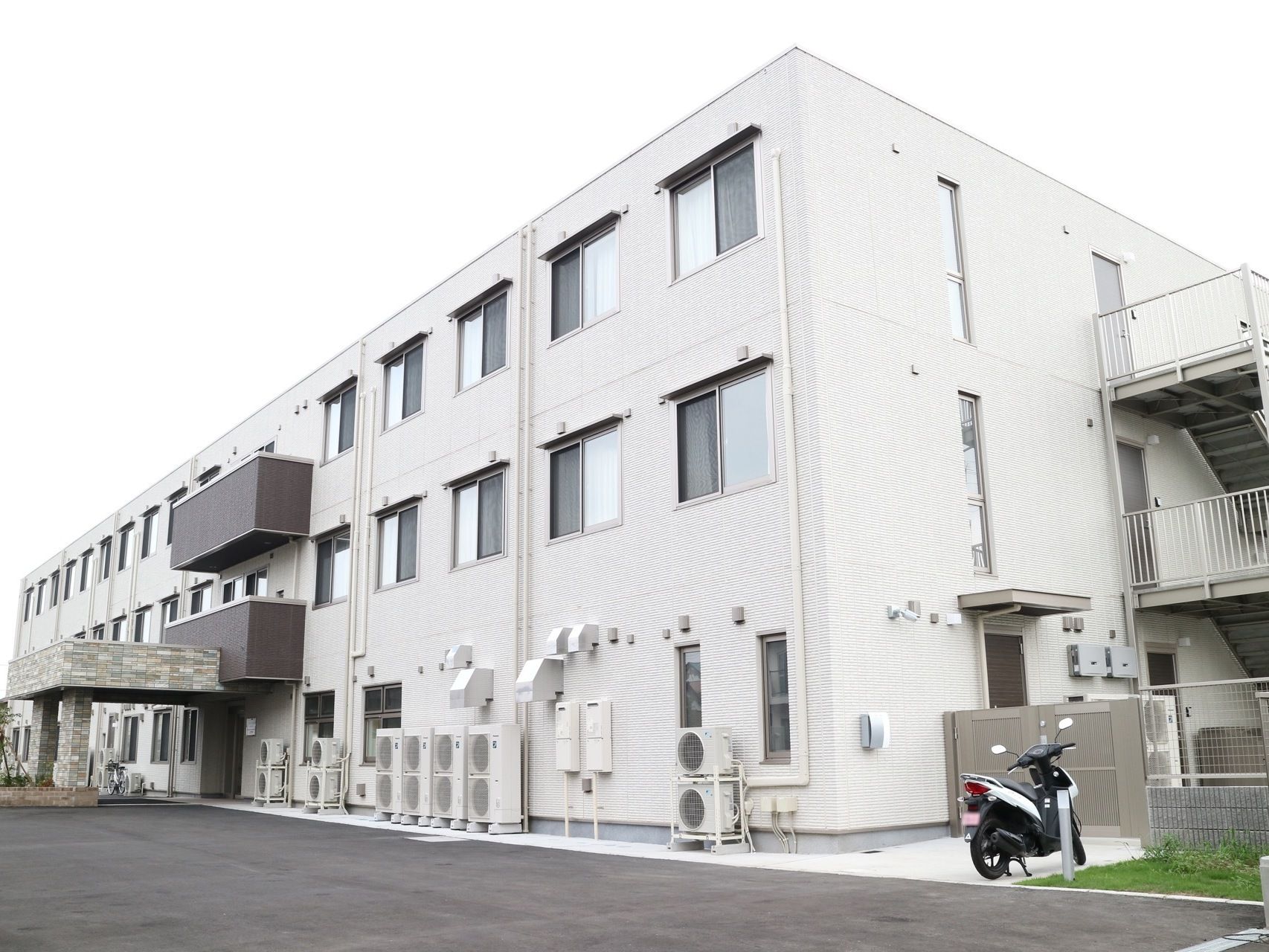 白色で統一された３階建ての施設である。玄関には車寄せがある。施設の目の前はとても広いスペースになっている。