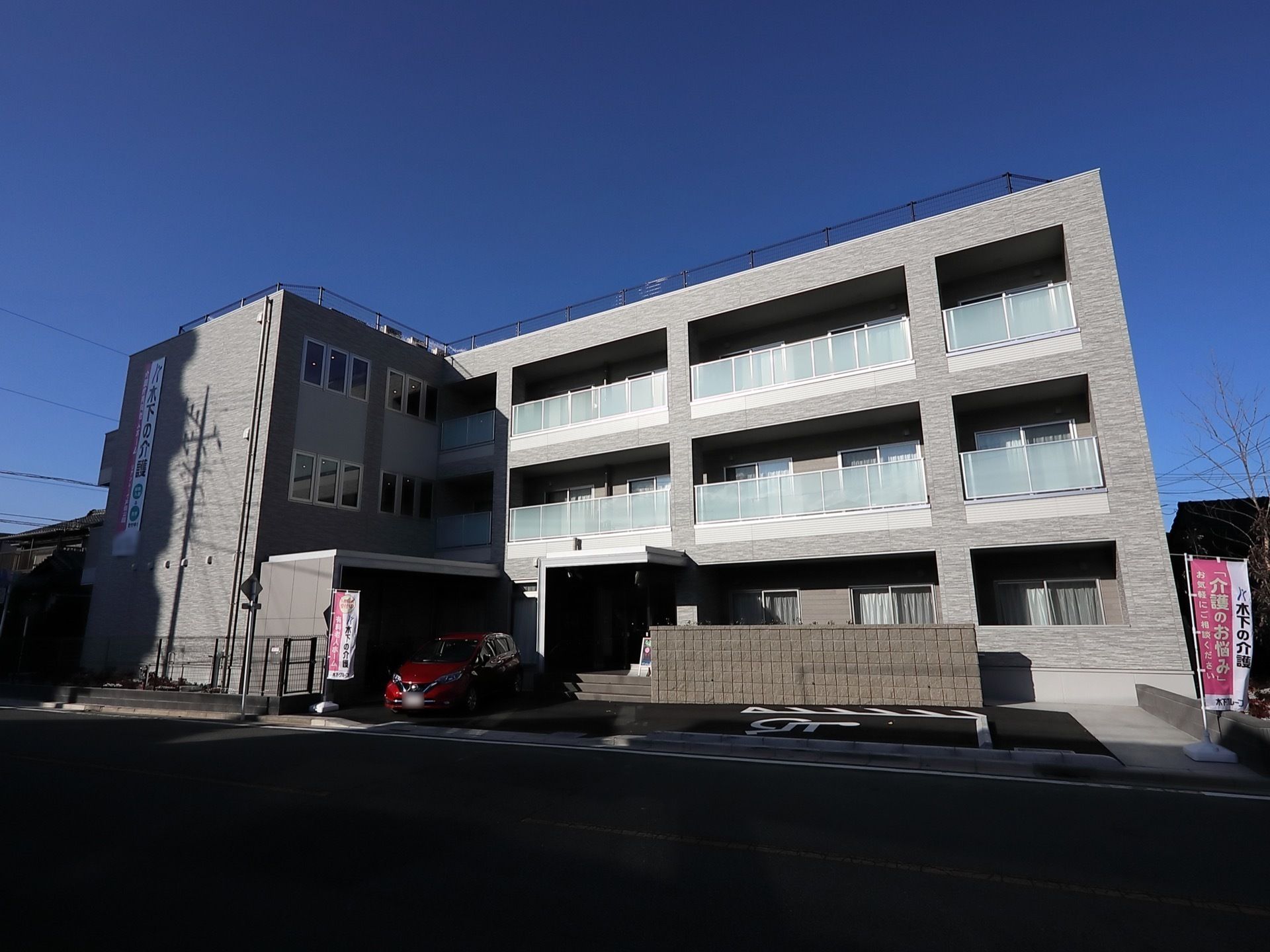 3階建てのどっしりとした建物。エントランス周辺には緑も植えられている。