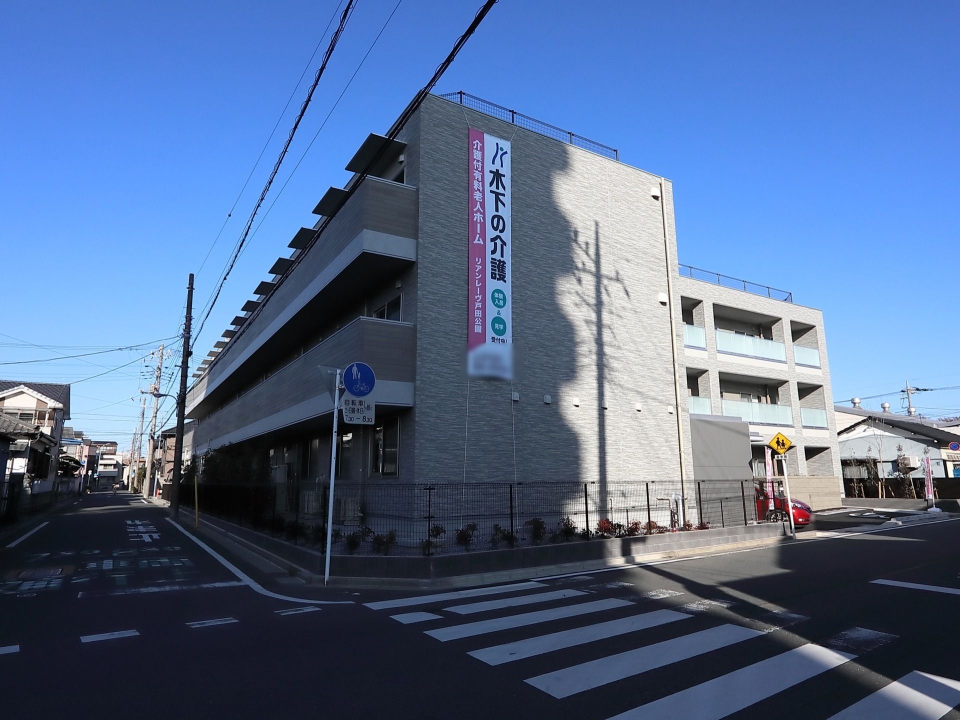 3階建ての建物。2階と3階にはベランダがあり、1階には駐車スペースもある。