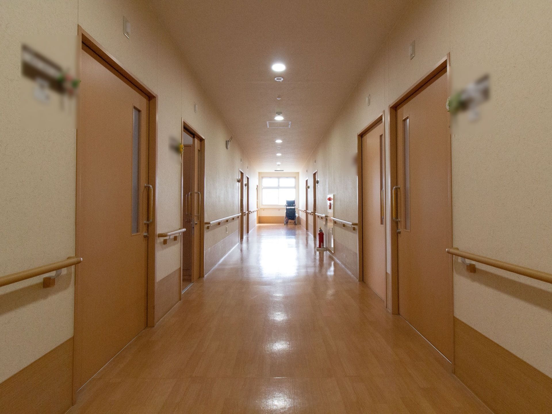 淡いブラウンの木目が美しい廊下である。両側の壁には手すり画完備され、防災対策としての消火器も設置されている。
