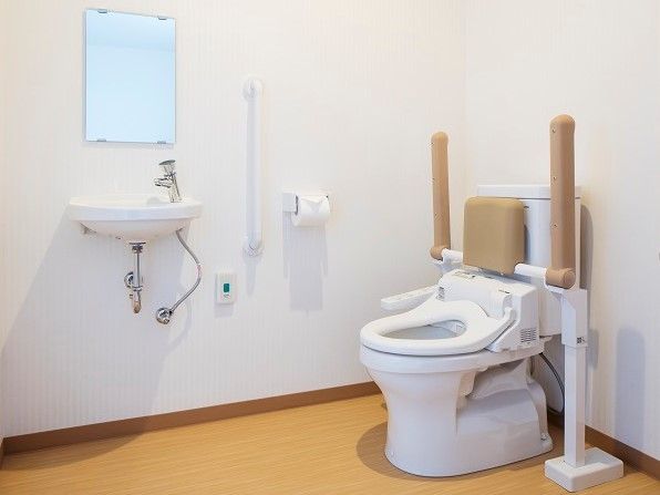 トイレの便座横には手すりがついているため、座り立ち動作が安心である。背もたれもついているので楽な姿勢を保つことができる。