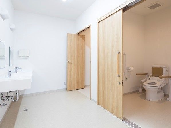 トイレの入口は広く、車椅子をご利用の方も入りやすい。扉は木目調の引き戸で、内部には手すりを設置している。