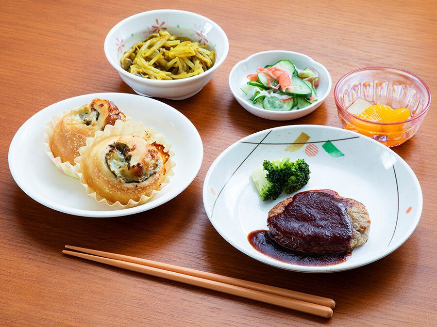 ハンバーグや総菜パン、きゅうりの和え物やフルーツのデザートのセット