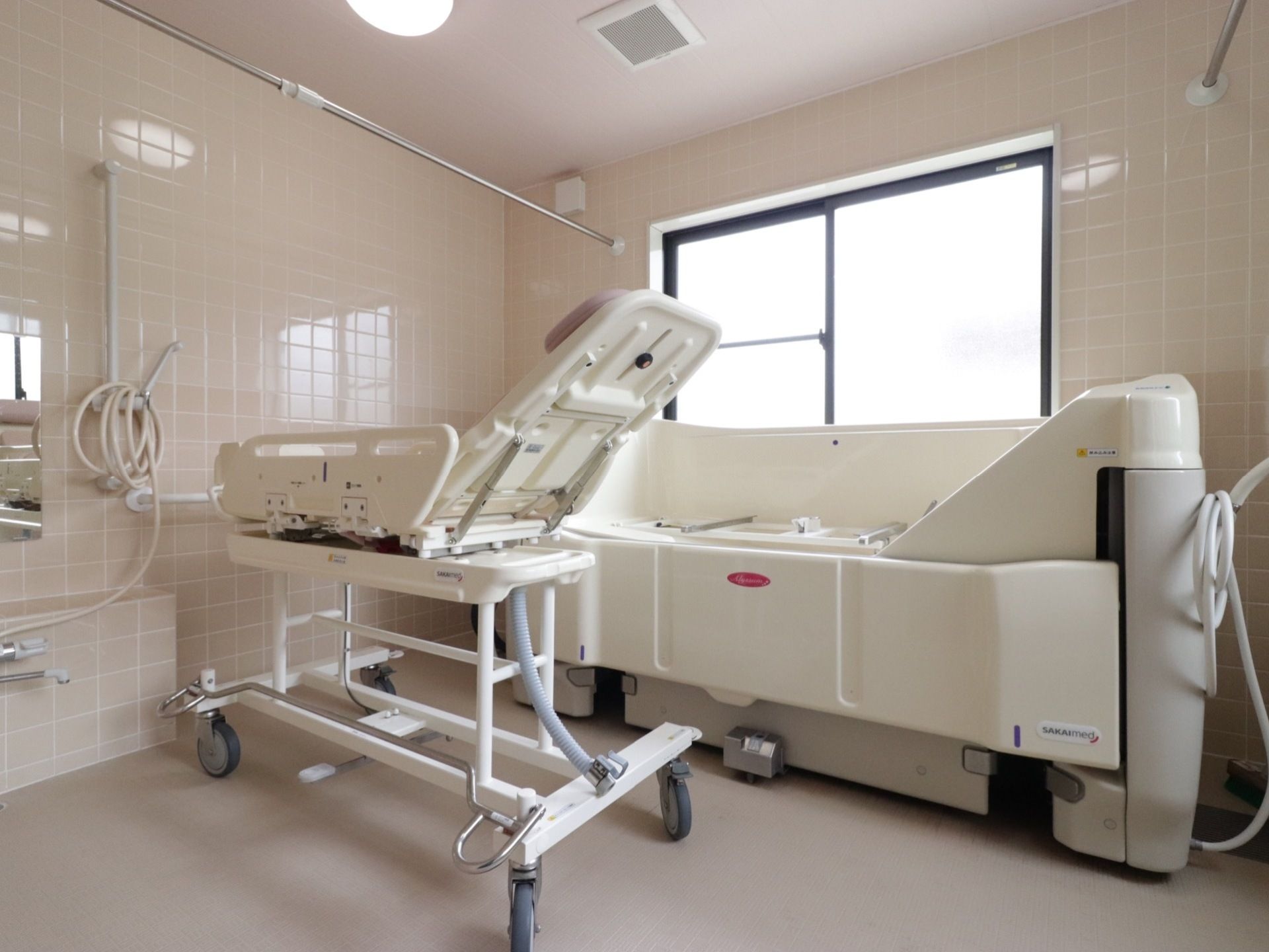 縁が稼働するタイプの機械式浴槽が設置された白い内装の浴室