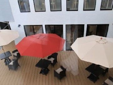 大きなパラソルの下にテーブル席を置いたウッドデッキ