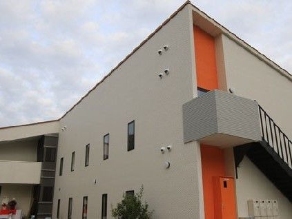 外階段の出入口にオレンジ色がワンポイントで使われた外観を持つ建物