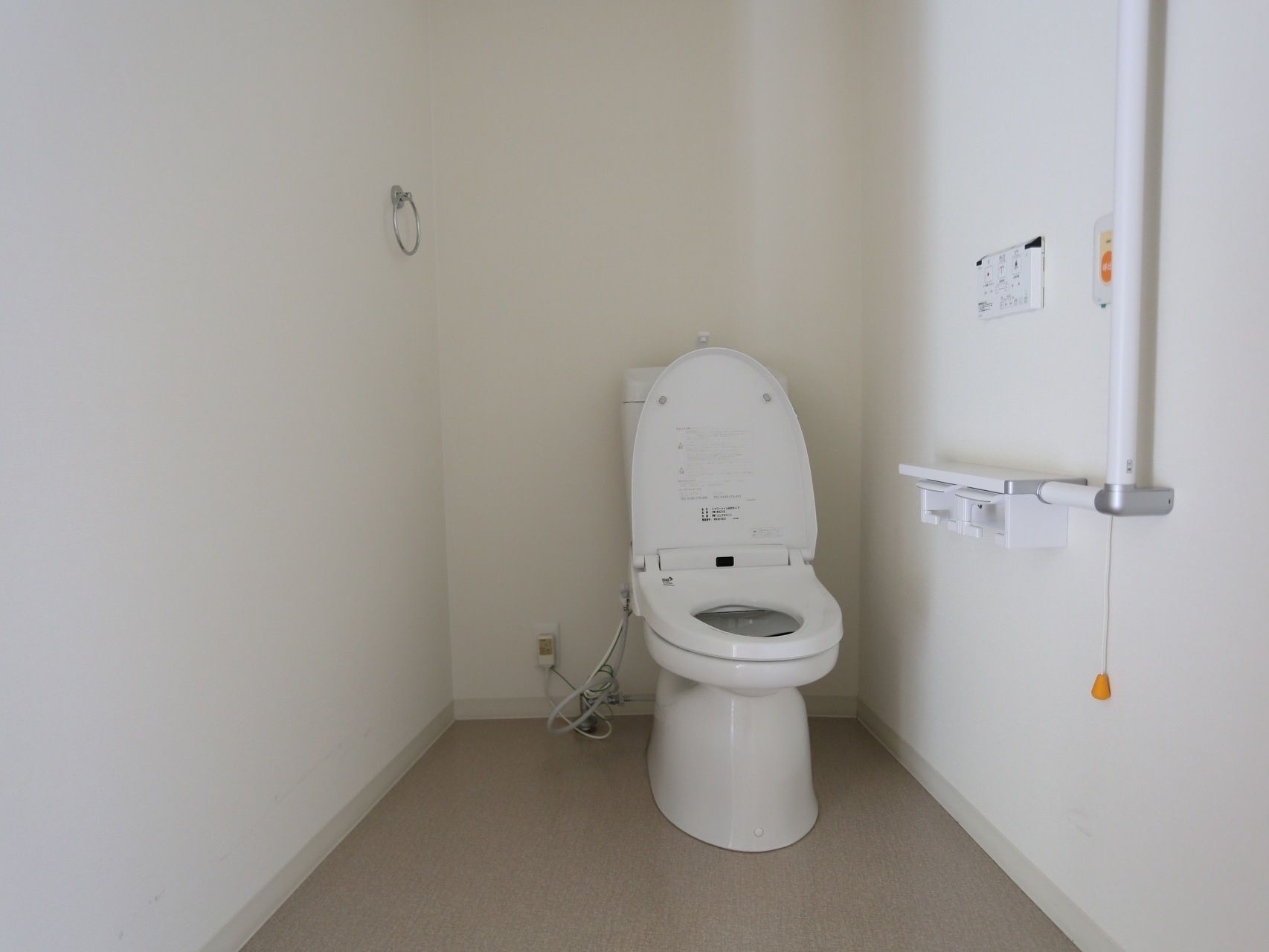 個室トイレは洋式便所タイプになっている。右手側の壁には手すりやナースコール、左手側にはタオル掛けが取り付けてある。