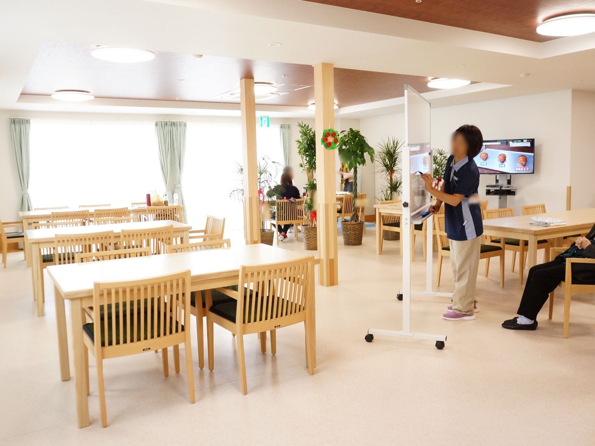 大きな窓があるので、明るく開放的な食堂である。白木のテーブルは間隔をあけて配置されている。テレビの設置もある。