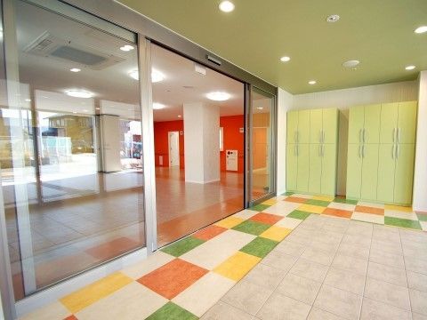 壁に沿ってカラフルな市松模様の床を敷いた、ガラス張りの自動ドア