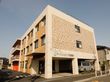 ３階建ての四角い建物。施設横には駐車場があり、アスファルトには横断歩道が書かれている。玄関横にワゴン車が停められている。