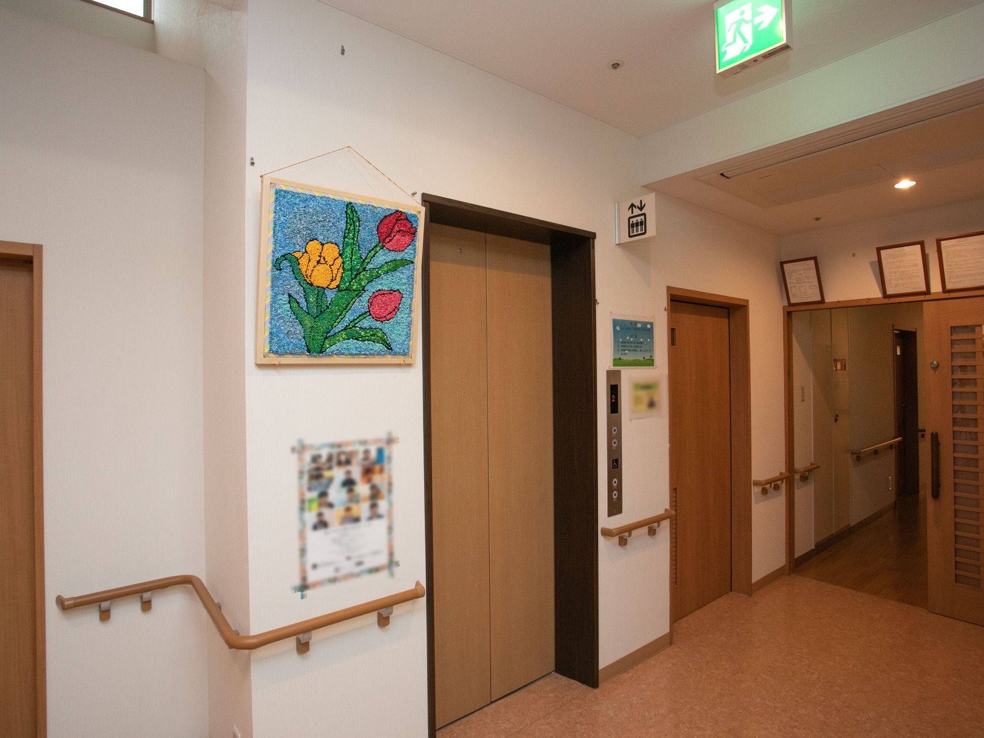 エレベーターが1基設置されている。壁にが入居者様が製作した作品が飾られており、手すりが備わっている。エレベーターホールは広々としている。