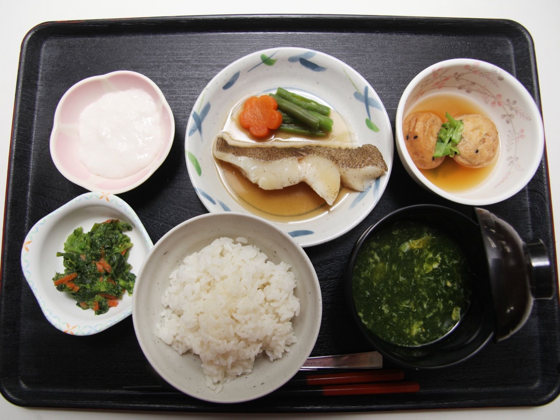 黒いトレイに白飯やあおさの味噌汁、野菜や白身魚を使用した栄養バランスが良く美味しそうなおかずが並べられている。