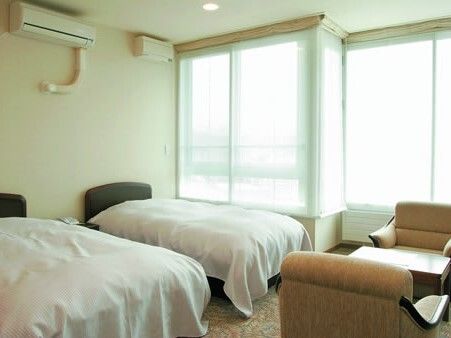 応接セットが置かれた部屋には寝具付きのベッドが二つ置かれ、大きな窓があり、明るい雰囲気。