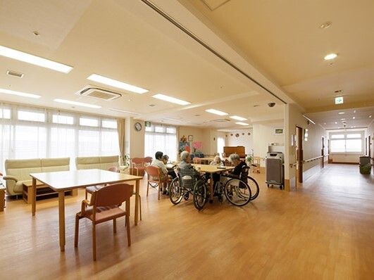 車いすの入居者たちが共有スペースのテーブルを囲んでいる。ゆったりとした配置となっているため、車いすでも行き来がしやすい。