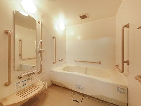 一人用の浴槽が設置された浴室にはベージュの手すりが多く付き、シャワースペースのそばには呼び出しボタンがついている。