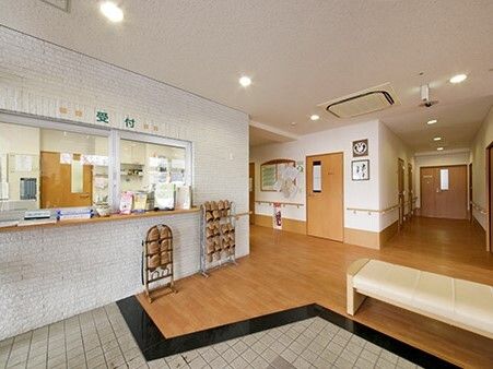 スリッパラックが複数置かれた玄関には「受付」と書かれた窓があり、パンフレットや消毒液が置かれている。