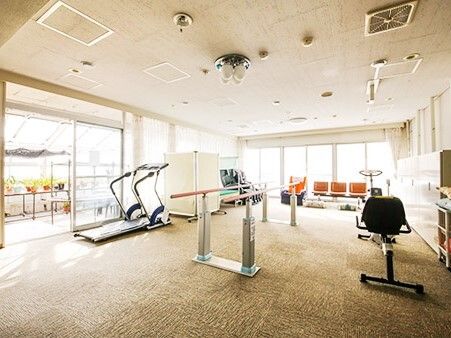 日当たりがよく、明るいリハビリスペースには様々なリハビリマシンが置かれ、中央には平行棒が設置されている。