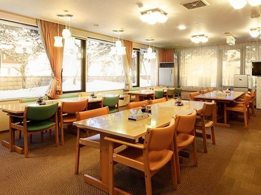 6人掛けのダイイングテーブルが複数置かれた食堂には大きな窓があり、窓の外には木が植えられている。