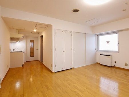 収納用のクローゼットやパネルヒーターが設置されたフローリングの部屋にはキッチンが付き、鏡も設置されている。