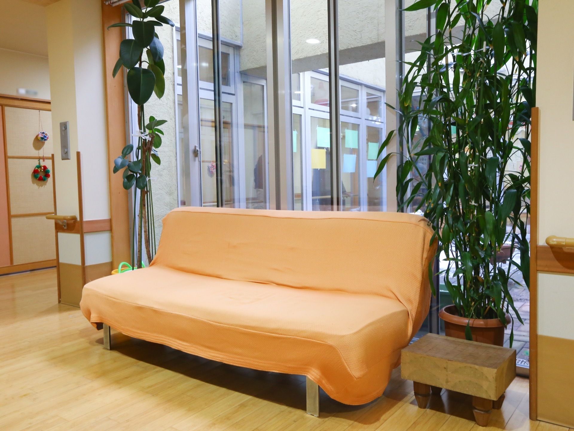談話コーナーには数人で座れるオレンジ色のソファが置かれており、その両サイドに背の高い観葉植物が配置されている。