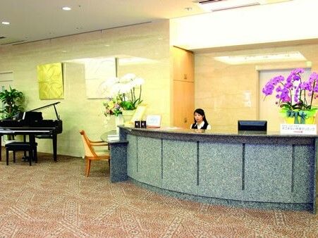 花が飾られたフロントには制服姿の女性スタッフがいて、そばにはグランドピアノも置かれている。